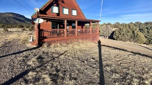 Una baita di legno con un balcone, un'antenna parabolica e una vista panoramica sul paesaggio circostante.