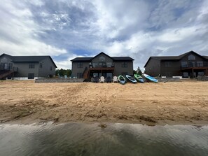 Propiedad frente al mar con varias casas, kayaks y sillas de playa.