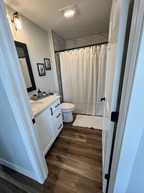 Ein Badezimmer mit Toilette, Waschbecken, Spiegel und Duschvorhang.