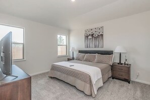 Un dormitorio con cama, mesitas de noche, televisor y ventana.