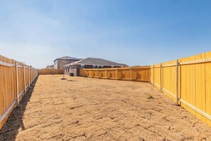 A fenced backyard with a house in the background. - Amazing Contemporary 4BR New Retreat ~ Fam&Group (Seagoville)