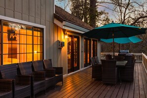 A wooden deck with wicker furniture and a grill, overlooking a forested area. - The Cove Lake House | Lakefront Vacation Rental Near Yosemite (Groveland)