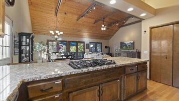 A spacious kitchen with a large island, wooden cabinets, and a high ceiling with exposed beams.