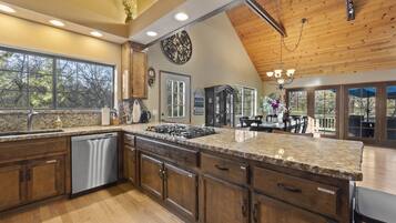 A spacious kitchen with granite countertops, wooden cabinets, and a stainless steel dishwasher.