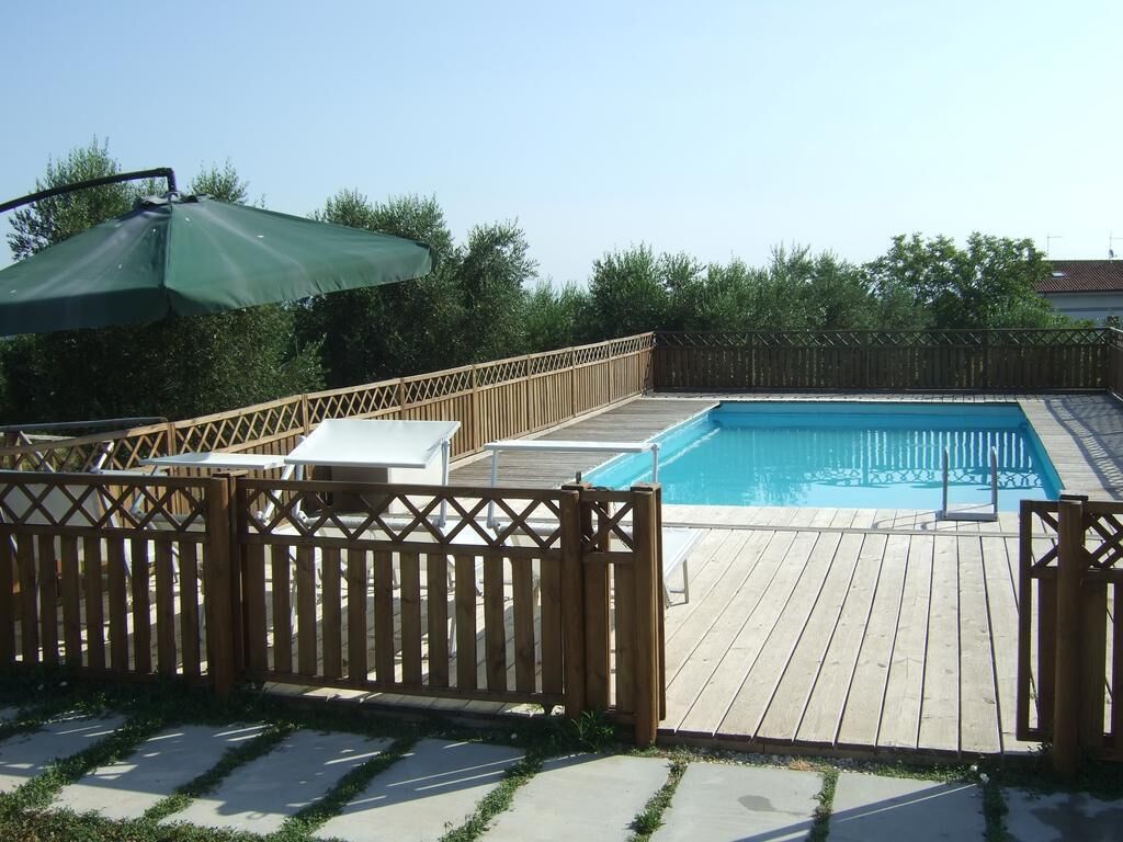 En træterrasse med en pool, omgivet af et træhegn og en parasol.