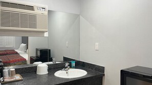 A modern bathroom with a white sink, a mirror, and a black countertop. - Studio 6 – Oakland, CA – San Francisco Berkeley Area (Oakland)
