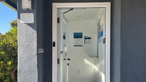 Eine Tür zu einem Gebäude mit einem Schild, das 'Toque El Timbre' und ein Rauchverbot sowie ein Verbot für Tabakwaren anzeigt.