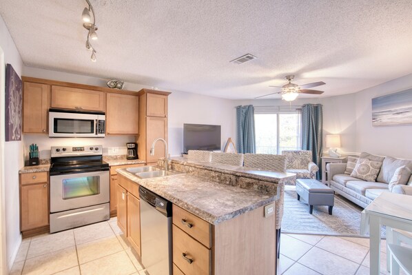 Enjoy cooking and relaxing in this well-appointed kitchen and living area with a central island, sofa, coffee table, and television.