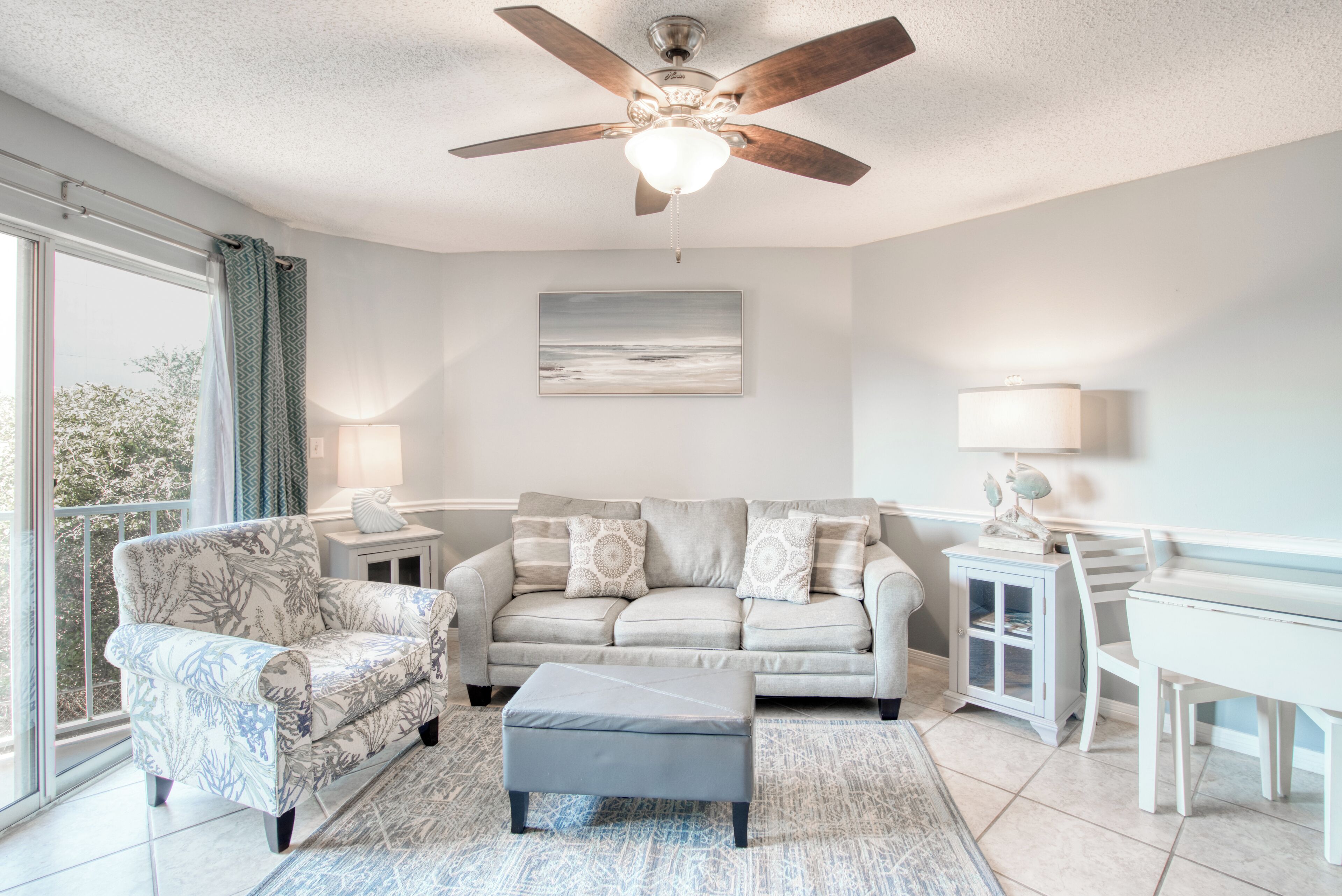 A living room with a ceiling fan, a sofa, a chair, a small table, and a cabinet.