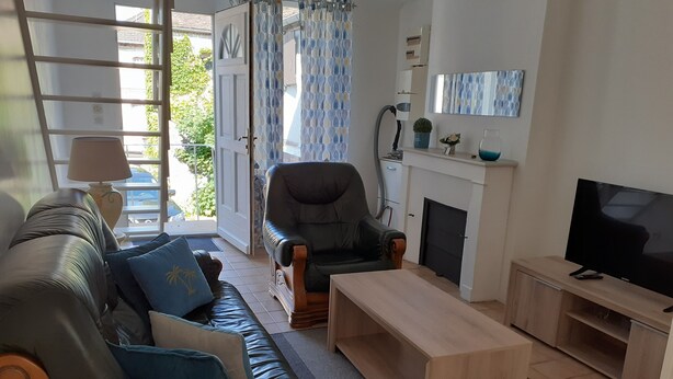 A living room with a sofa, armchair, coffee table, TV, fireplace, and a view of the outdoors.
