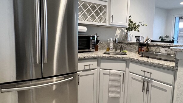 Una cocina moderna con armarios blancos, electrodomésticos de acero inoxidable y encimera de granito.