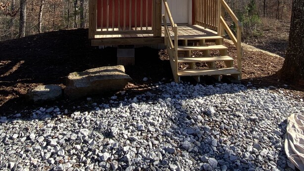 A small, single-story cabin with a red exterior and a wooden porch.