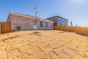 A residential area with a brick house, a wooden fence, and a dry lawn.