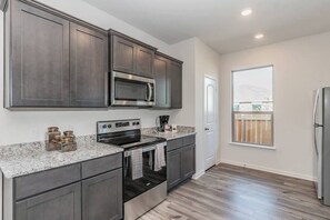 A modern kitchen with dark cabinets, stainless steel appliances, and a granite countertop.
