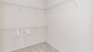 Ein Zimmer mit weißen Wänden und Teppichboden, ausgestattet mit zwei Drahtregalen an den Wänden.