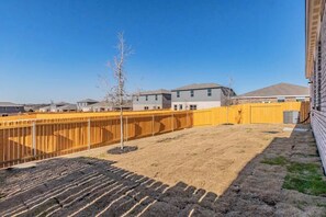Zona residencial con casas, un patio cercado y cielo despejado.
