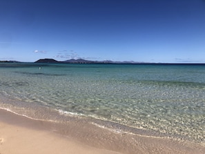 A beach with clear shallow waters and distant mountains. - VILLA WITH A VIEW; by MAHBO. (B) (La Oliva)