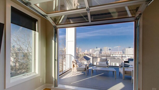 A modern apartment with a large sliding glass door leading to a balcony with outdoor seating. - Panoramic View- 8 Comfy Beds - Multilevel Townhome (Nashville)
