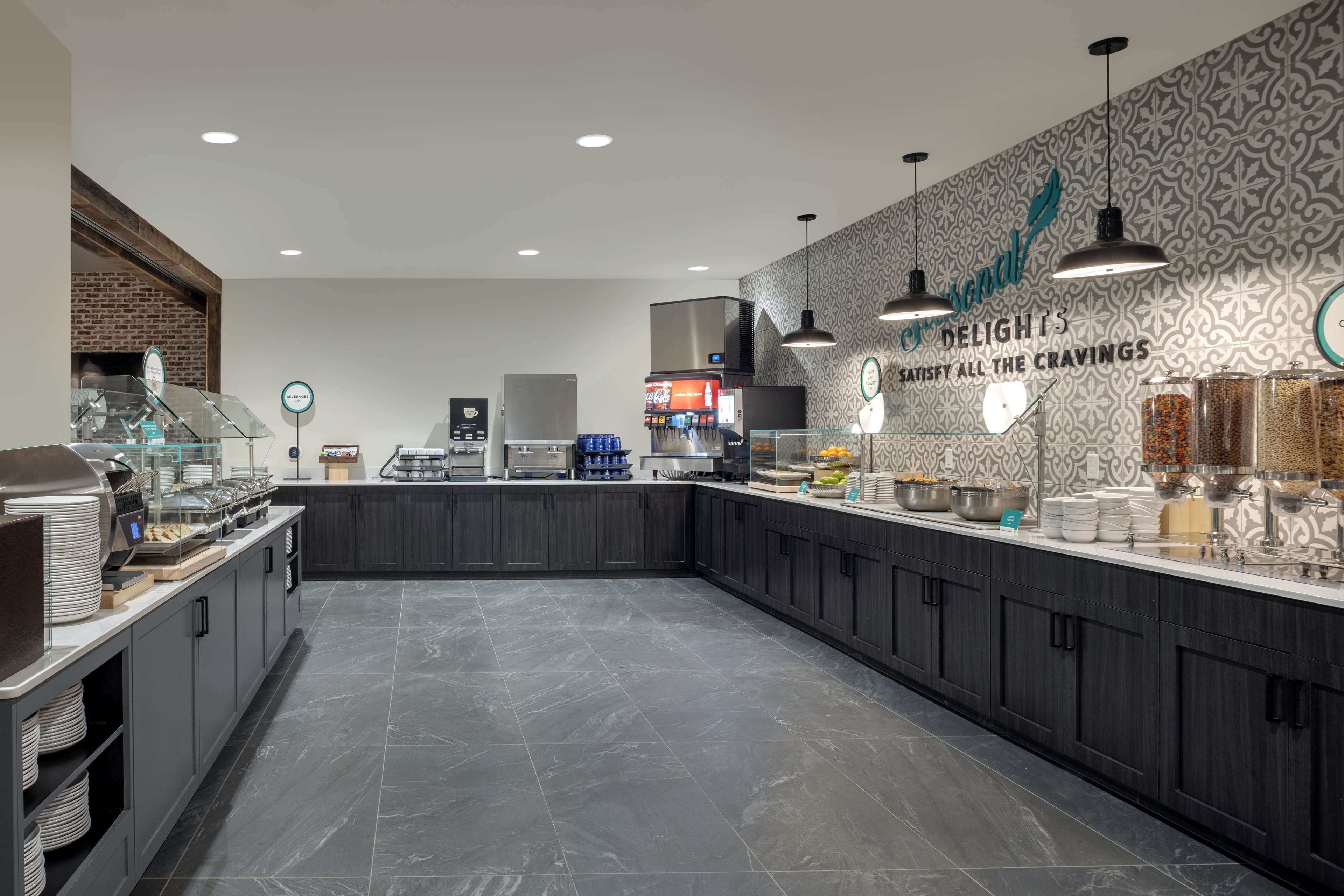A modern kitchen area with a buffet setup, including a coffee machine, food display, and various food containers.