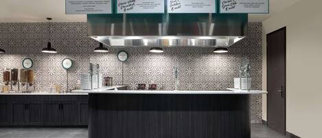A modern kitchen with a central island, a patterned backsplash, and a menu board above displaying four breakfast options.