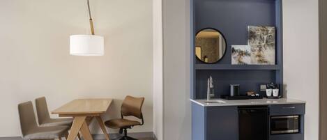 A modern kitchen with a blue cabinet, a round mirror, and a coffee machine.