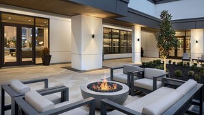 An outdoor seating area with a fire pit, modern furniture, and a view of the building's interior. - Embassy Suites by Hilton Bowling Green (Bowling Green)