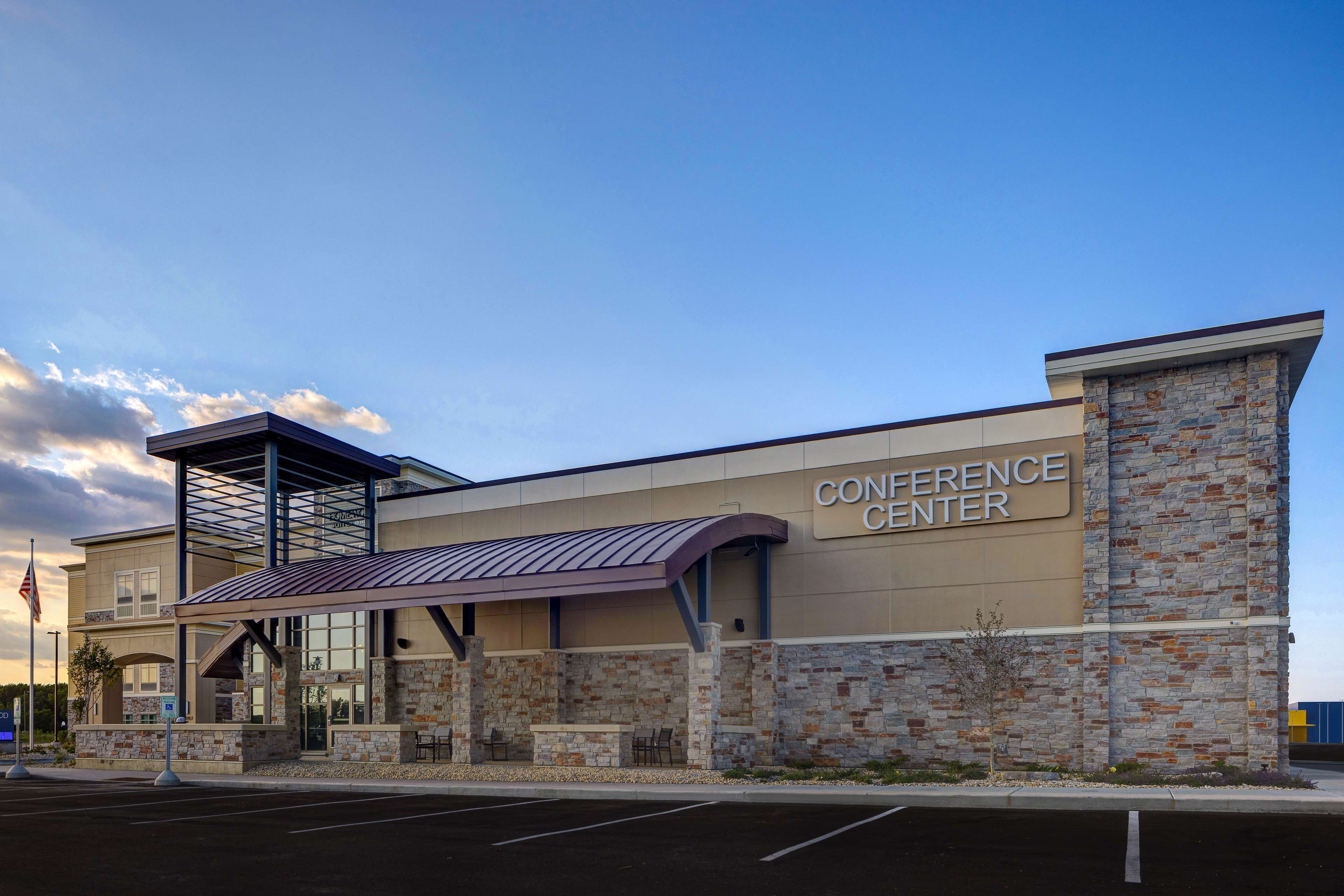 A conference center with a stone facade, a covered entrance, and an American flag.
