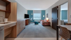 Une chambre d’hôtel moderne dotée d’une kitchenette, d’un coin repas et d’un espace salon offrant une vue sur la ville.