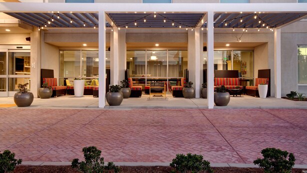 L’entrée d’un hôtel, avec un espace extérieur abrité aménagé en coin salon, de grands pots de plantes et un chemin pavé.
