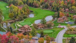 Un campo de golf con club house, estanques y árboles de colores otoñales.