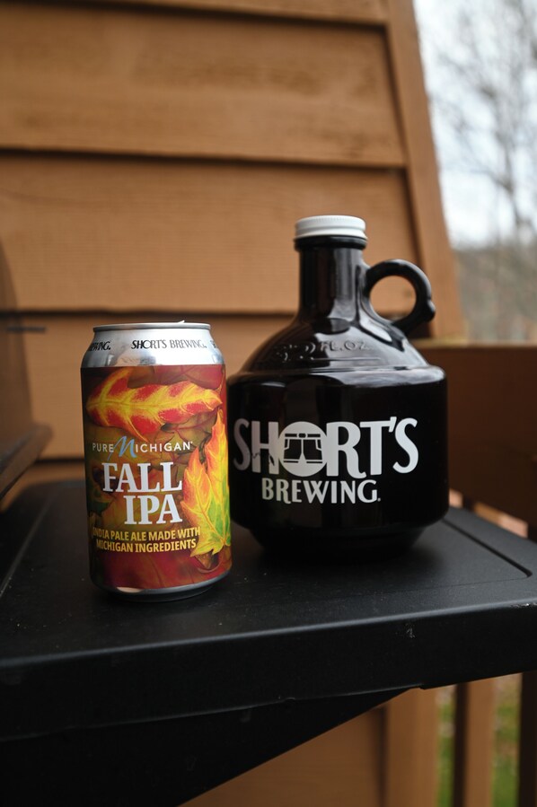 A can of Pure Michigan Fall IPA and a black Short's Brewing jug on a black surface.