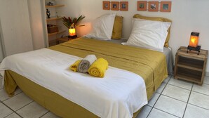 A bedroom with a bed, pillows, a nightstand, a shelf with decorative items, and a skylight.