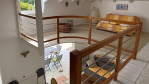 A spacious loft bedroom with a high ceiling, a bunk bed, a dining area with a table and chairs, and a view of the outdoors.