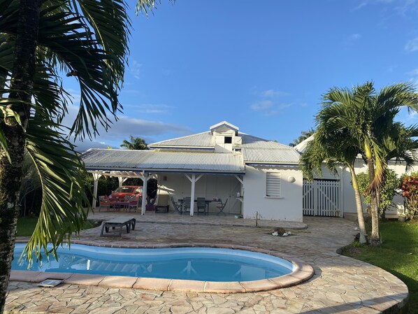 A house with a swimming pool, outdoor furniture, and a covered patio area.