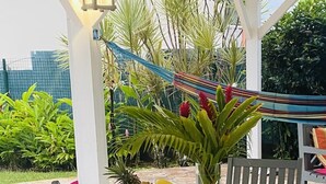An outdoor dining area with a table set for breakfast, including fruits, bread, and beverages.
