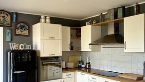 A modern kitchen with white cabinets, a black refrigerator, and a wooden countertop.