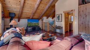 A cozy living room with a fireplace, leather sofa, and a television. - Edelweiss - Remodeled Luxury 3 BR with Private Hot tub (Tahoe City)