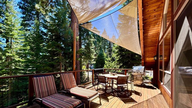 A wooden deck with outdoor furniture, a grill, and a view of a forest. - Edelweiss - Remodeled Luxury 3 BR with Private Hot tub (Tahoe City)