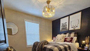 Una camera da letto con un letto, un comodino, una lampada, uno specchio e una lampada a sospensione.