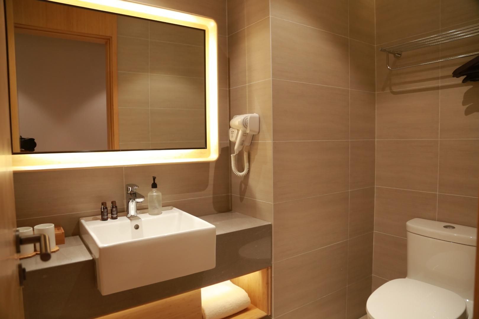 Un baño con lavamanos blanco, un espejo, un secador de pelo y un inodoro.