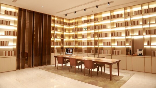 Una biblioteca moderna con una gran mesa de madera y sillas, rodeada de estanterías con iluminación integrada.