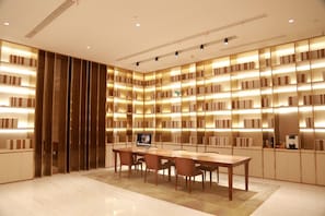 Una biblioteca moderna con una gran mesa de madera y sillas, rodeada de estanterías con iluminación integrada.