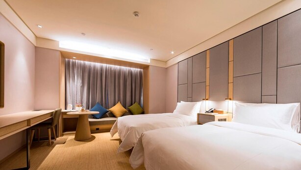 A hotel room with two beds, a desk, a chair, a small table, and a window with curtains. - Ji Hotel (Taiyuan)
