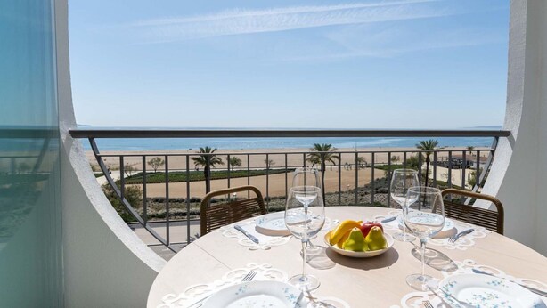 A dining table with a view of the beach and ocean. - Nice apartment for 2 people with A/C, WIFI, TV, terrace and pets allowed (Empuriabrava)