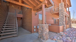 Une cabane en bois avec une cheminée en pierre, un escalier en bois et un balcon.