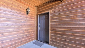 Une façade en bois avec une porte sombre et un paillasson en métal.