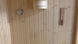 A wooden sauna with a bench, a thermometer, and a water gauge. - 50.1.m Ankerplatz - Moderne, Hochwertige Ferienwohnung, Sauna, Großer Balkon, Strandnah (Wangerland)