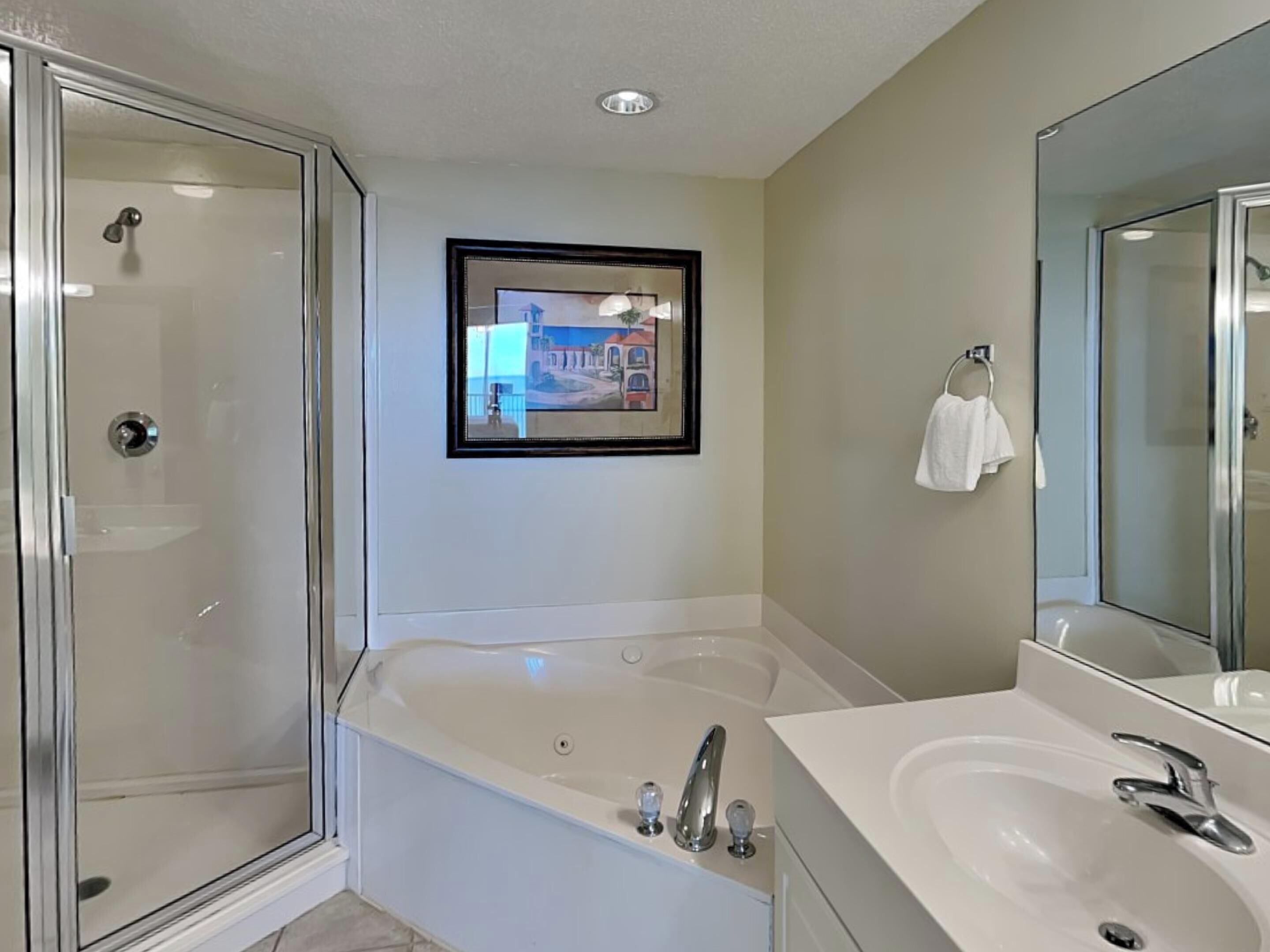 Une salle de bain moderne avec une douche à parois de verre, une grande baignoire et un meuble-lavabo avec un miroir.