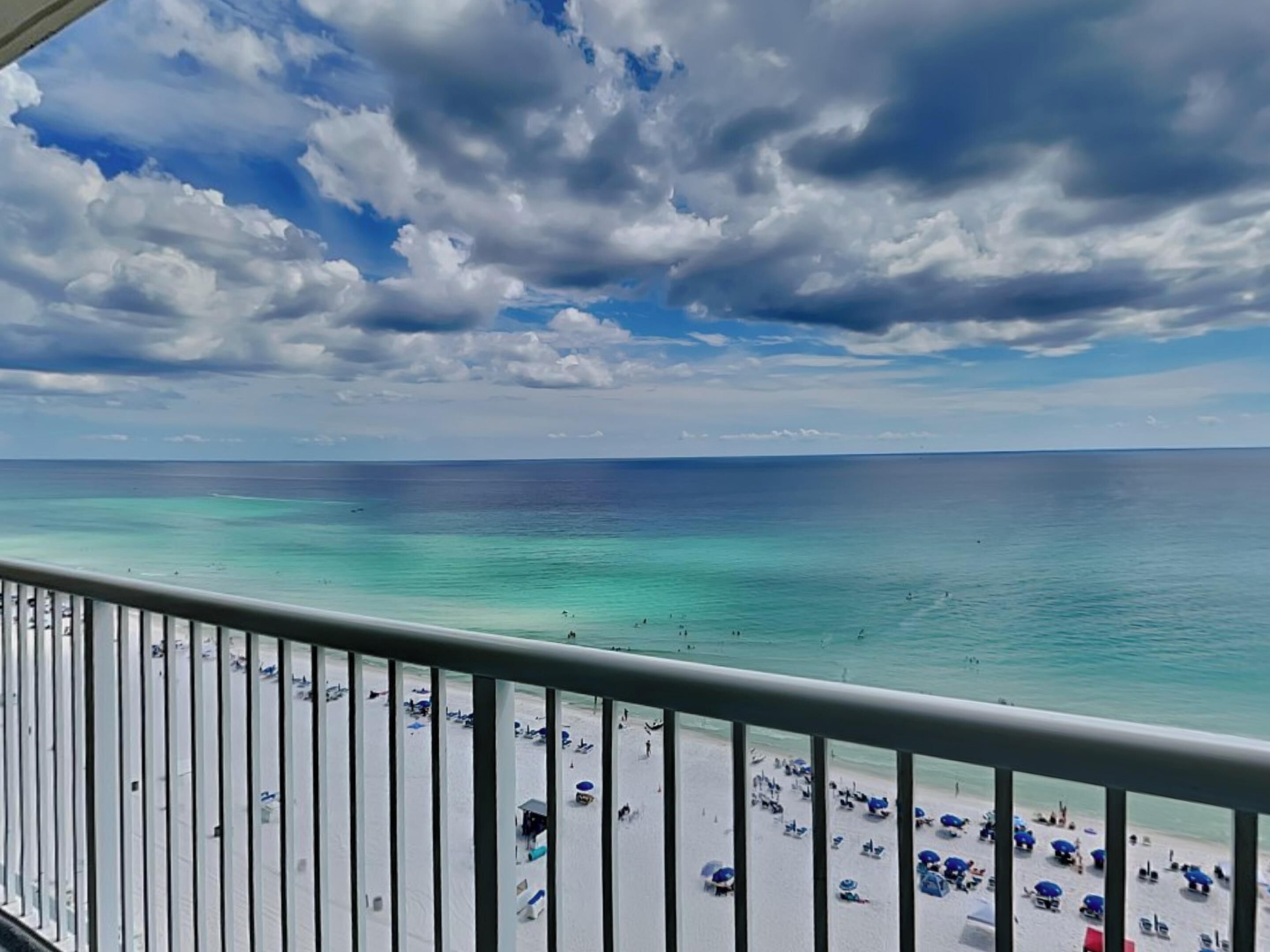 A beach with clear turquoise water and a cloudy sky.