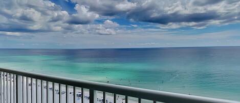 A beach with clear turquoise water and a cloudy sky.